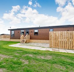 A wooden cabin with steps and a fenced area at Beech Waterside Spa Carlton Miniott near Thirsk