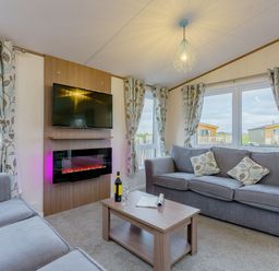 A living room with a sofa and television at Larch Waterside Spa (Pet) Carlton Miniott near Thirsk