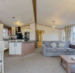 A living room with a sofa and dining table in Larch Waterside Spa (Pet) Carlton Miniott near Thirsk
