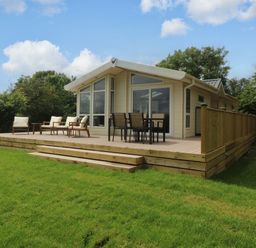 An outdoor area with a lodge and seating at Plas Marchog Lodge, Rhoscefnhir near Pentraeth