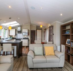 A living room with sofa and kitchen island at Plas Marchog Lodge Rhoscefnhir near Pentraeth