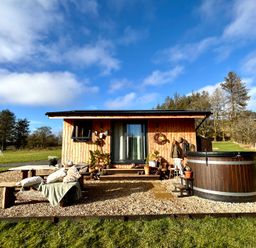 A cabin with a hot tub and chairs on the deck at Harriet in Llangurig