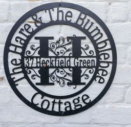 A sign displaying the name and address at The Hare & the Bumblebee Cottage in 37 Heckfield Green