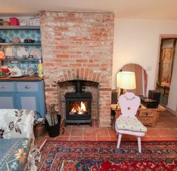 A living room with a stove and a bookshelf at The Hare & the Bumblebee Cottage