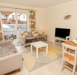 A living room with a sofa, table, and television at Harbour View Poole