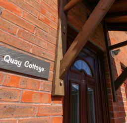 A nameplate on a brick wall identifying Quay Cottage in Poole