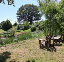 A seating area with chairs near a body of water at Captains Barn in Tiverton
