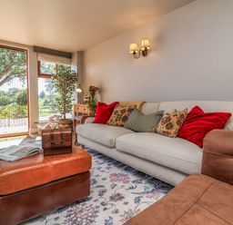 A living room with a sofa and plants at Captains Barn in Tiverton