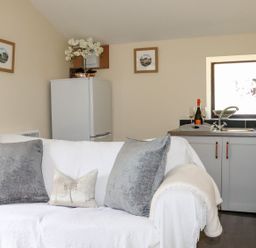 A kitchen with a sofa and refrigerator at Lannlyvri Lodge, Lanlivery near Lostwithiel