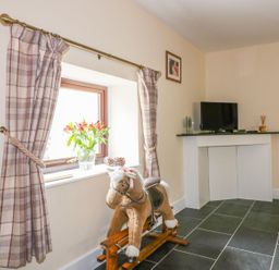 A living room with a rocking horse and television at Camellia Cottage in Bodmin