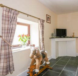 A snug with a rocking horse and television at Camellia Cottage in Bodmin