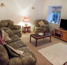 A living room with sofas, a coffee table and a television at Tyddyn Gyrfa Cottage Cemaes Bay