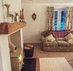 A living room with a couch and fireplace at Tyddyn Gyrfa Cottage Cemaes Bay