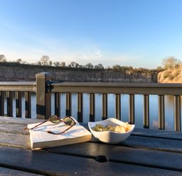 A table with a book and snacks near water at Pods by the Lake in Penrith