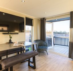 A living room with a television and dining table at Pods by the Lake in Penrith