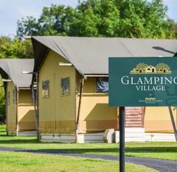 Sign for Glamping Village at Ullswater Heights with glamping tents in the background
