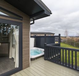 An outdoor deck with a hot tub and dining area at Helvellyn (Pet) Penrith
