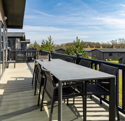 A deck with a table and chairs overlooking other houses at Scaféll (Pet), Penrith