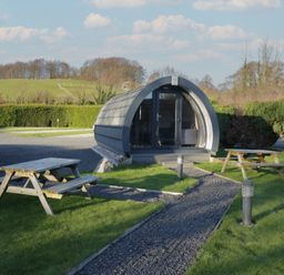 An outdoor area with a glamping pod and picnic tables at Pod 6 (No Pets) Tewitfield