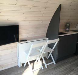 A kitchen with a television, a folding table with chairs, and appliances at Pod 9 (No Pets) in Carnforth