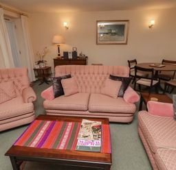 A living room with sofas and a dining table at Grange Cottage in Belford