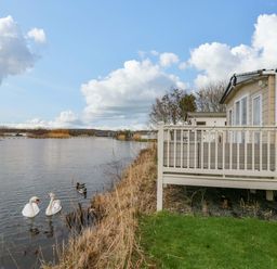 A deck by the water with swans and ducks at 62 Guddlebeck in Flookburgh