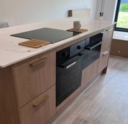 A kitchen with an island featuring a cooktop and ovens at 81 Lon Gogarth Benllech