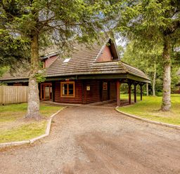 A cabin exterior with a driveway and trees at Eagle Spa Plus in Dundee