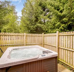 A hot tub in a garden area surrounded by a wooden fence at Eagle Spa Plus (Pet) Dundee