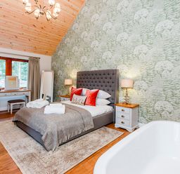 A bedroom with a bed and a tub at Byron Premier Spa (Pet) Dundee
