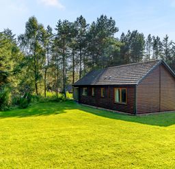A house surrounded by trees and grass at Muirloch Spa Plus (Pet) in Dundee