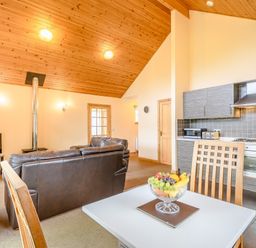 A living room with a sofa and kitchen counter at Muirloch Spa Plus (Pet) Dundee