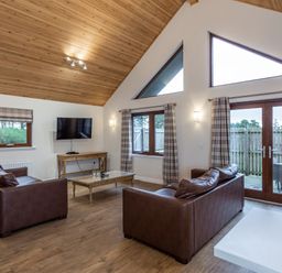 A living room with a sofa and television at Raeburn Premier Spa in Dundee