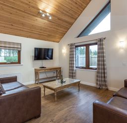 A living room with a TV and sofa at Raeburn Premier Spa in Dundee