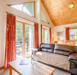 A living room featuring a sofa, a table, and large windows at Osprey Lodge in Dundee