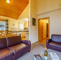 A living room with a sofa and dining area at Osprey Lodge (Pet) Dundee