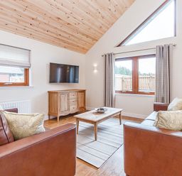 A living room with a sofa, table, and television at Galbraith Premier Spa (Pet) in Dundee