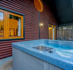 An outdoor area with a hot tub and windows at Osprey Spa Plus Dundee
