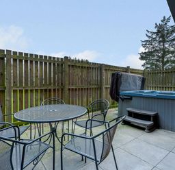 An outdoor area with a hot tub and a table with chairs at Osprey Spa Plus in Dundee