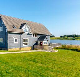 A house with a balcony by a lake at Lochside Premier Spa in Dundee