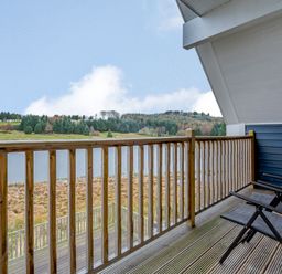 A balcony with chairs overlooking a lake at Lochside Premier Spa in Dundee
