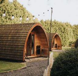 Wooden pods with tables and chairs in a garden at Garden Pod VIP Waltham