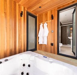 A bathroom with a hot tub and wooden walls at Dream View in Waltham