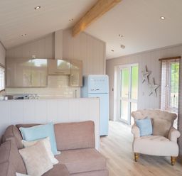 A living room with kitchen area and white chair at The Henley in Waltham
