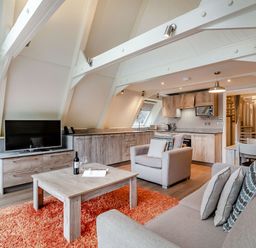A living room with a television and kitchen units at St Ives Studio Spa, Praze-An-Beeble