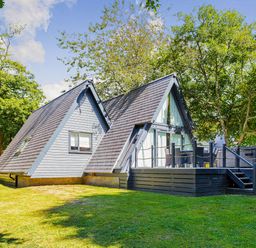 A house with a deck surrounded by trees at St Ives Lodge 3 Spa in Praze-An-Beeble