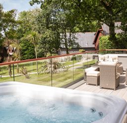 An outdoor space with a hot tub and seating area at Aubyn Lodge Spa Praze-An-Beeble