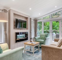 A living room with a television and seating at Aubyn Lodge Spa in Praze-An-Beeble