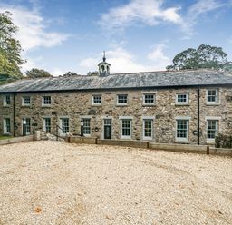 A stone building with windows and a gravel driveway at Coach House in Praze-An-Beeble