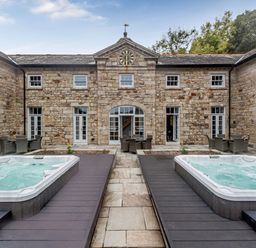An outdoor area with two hot tubs and seating at Coach House in Praze-An-Beeble